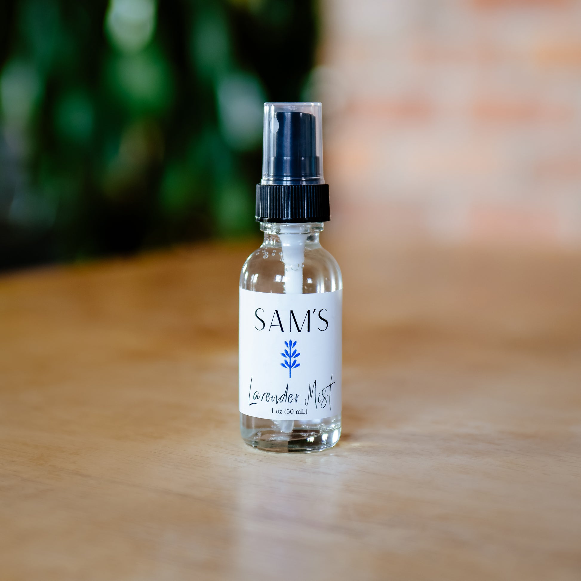 A clear glass spray bottle labeled 'SAM'S Lavender Mist' with a black spray nozzle, containing distilled water and lavender essential oil.