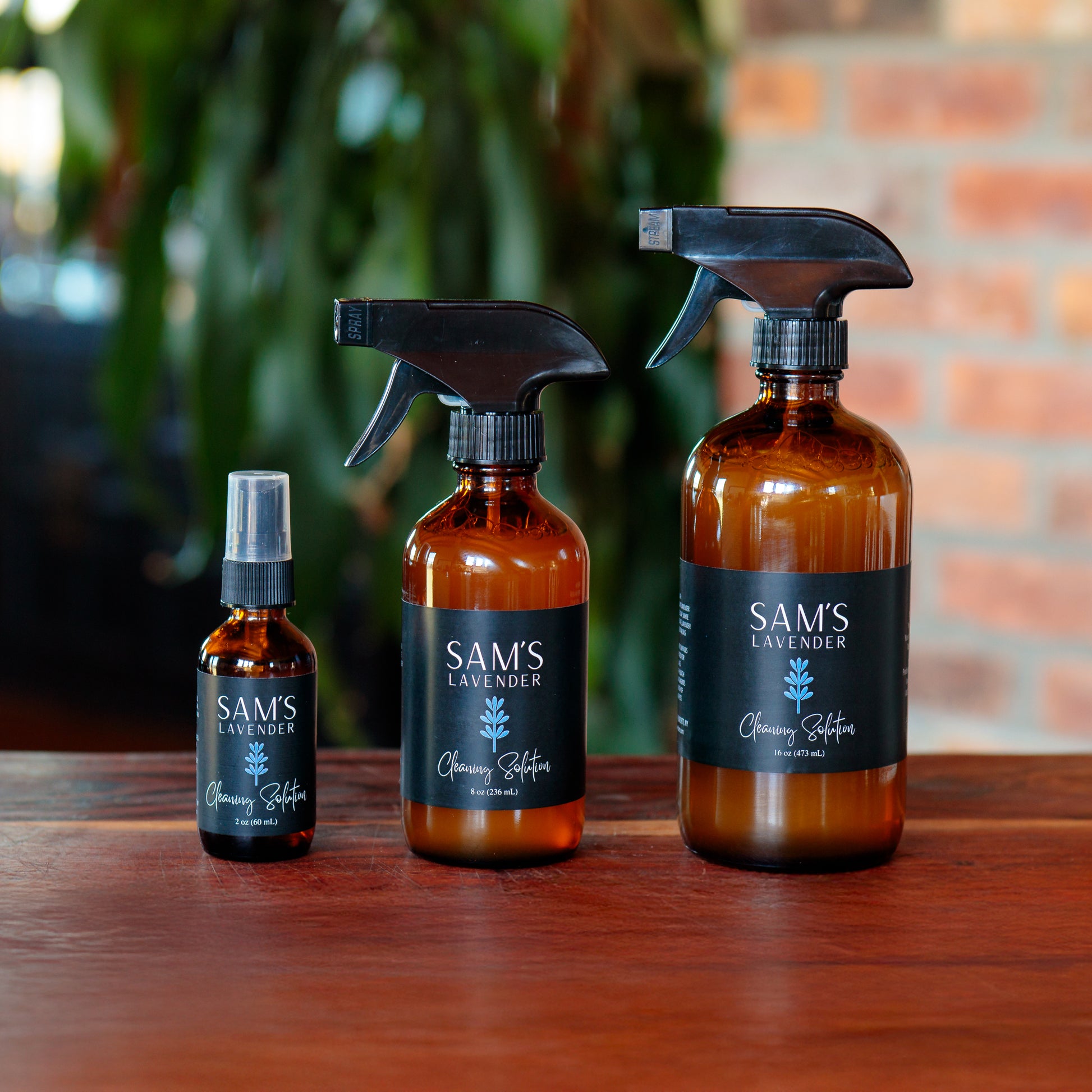 Lineup of three amber glass bottles of Sam's Cleaning Solution - 2oz, 8oz, and 16oz sizes