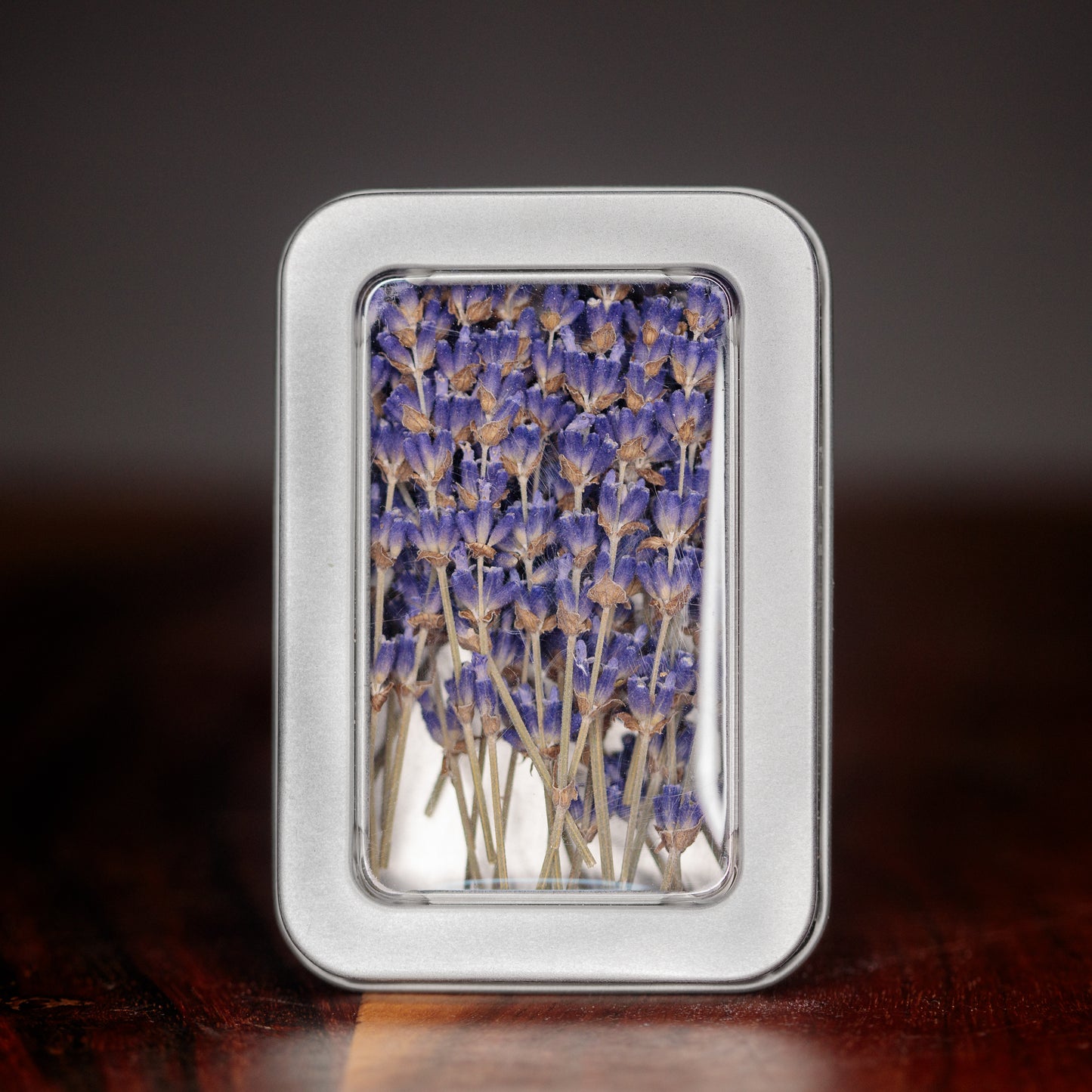 A rectangular container holding dried culinary lavender sticks against a dark background.